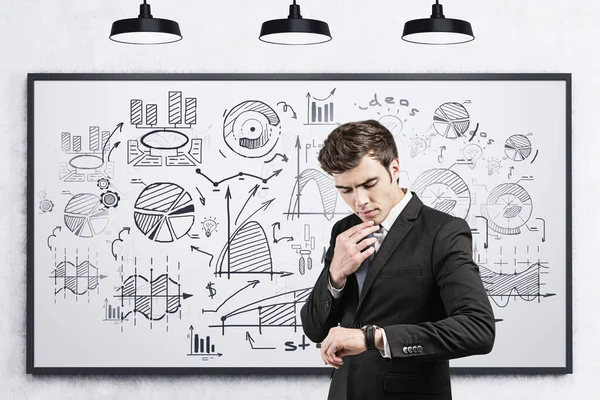 Pensativo Jovem Empresário Europeu Olhando Para Seu Relógio Perto Whiteboard — Fotografia de Stock