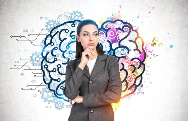 stock image Pensive young businesswoman standing near concrete wall with creative and analytical brain sketch drawn on it. Concept of brainstorming