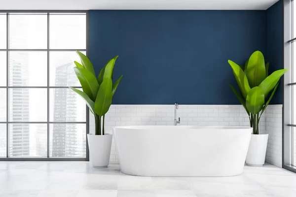 Interior of stylish bathroom with blue and white brick walls, tiled floor, comfortable white bathtub and two big potted plants. Window with blurry cityscape. 3d rendering
