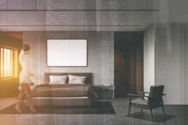 Beyaz duvarları, beton zemini, üzerinde poster ve koltuk modeli olan rahat yatağı olan şık bir yatak odasında yürüyen bulanık, genç bir kadın. Renkli resim çift pozlama