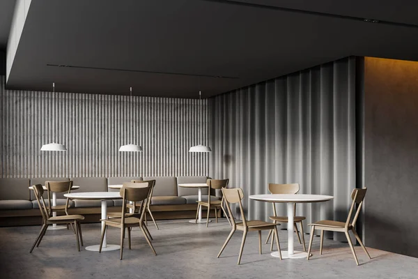 Corner of stylish loft coffee shop with grey walls, concrete floor, round tables with wooden chairs and comfortable grey sofa near the wall. 3d rendering