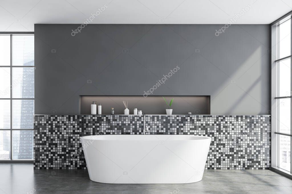 Interior of modern bathroom with grey mosaic walls, concrete floor, window with blurry cityscape, cozy bathtub and shelf with beauty products. 3d rendering
