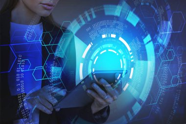 Tanımlanamayan genç iş kadını gri arka planda tablet kullanıyor ve fütüristik HUD arayüzü iki kez kullanılıyor. Yüksek teknoloji ve büyük veri kavramı. Tonu ayarlanmış resim