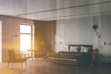 Güneşli İskandinav yatak odası köşesinde beyaz ve ahşap duvarları, rahat kral yatağı ve bilgisayar masalı ev ofisi olan bulanık genç bir kadın. Renkli resim çift pozlama