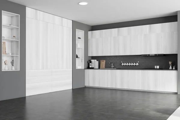 Corner of modern kitchen with gray brick walls, concrete floor, white wooden cupboards and countertops with built in sink and cooker. 3d rendering