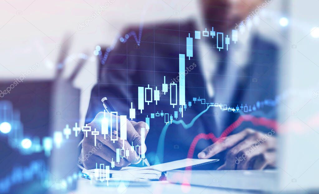 Blurry African American businessman taking notes at table with double exposure of blurry digital graphs. Concept of consulting and stock market. Toned image