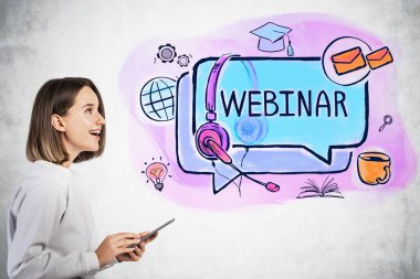 Üzerinde renkli çizimler olan, beton duvarın yanında duran, günlük kıyafetlerle mutlu genç kızın yan görüntüsü.