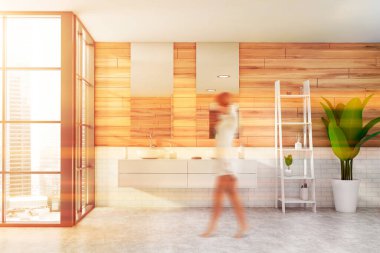 Geniş banyoda, tahta ve beyaz tuğlalı duvarları, beton zemini, iki aynası ve güzellik ürünleriyle dolu rafları olan rahat bir çift lavabosu olan bulanık genç bir kadın. Tonu ayarlanmış resim