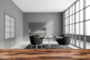 Ürününüz için ahşap masa bulanık panoramik yemek odasında gri duvarları, beton zemini, siyah koltukları ve kapısı olan rahat masası arka planda mutfağı olan. 3D oluşturma maketi