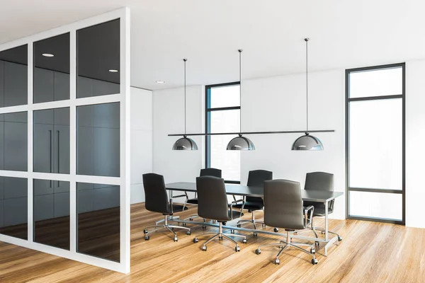 Corner of modern meeting room with white and glass walls, wooden floor and long conference table with black armchairs. Windows with blurry cityscape. 3d rendering
