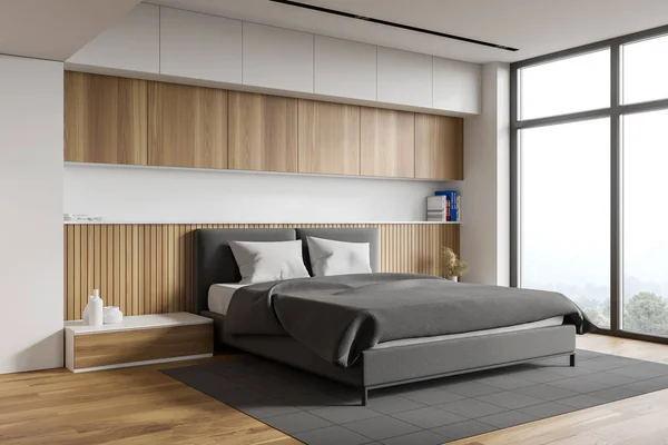 Corner of comfortable master bedroom with white and wooden walls, wooden floor, king size bed standing on grey carpet and two bedside tables. Blurry mountain view. 3d rendering