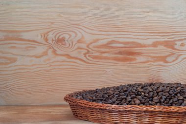 Tahta arka planda hasır tabaktaki kahve taneleri