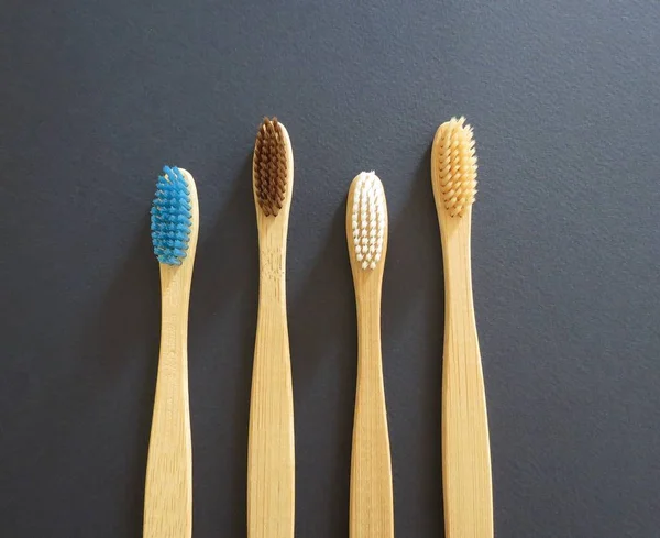 Conjunto de quatro escovas de dentes de bambu ecológicas no fundo escuro. Conceito de desperdício zero, orgânico, eco friendly shopping — Fotografia de Stock