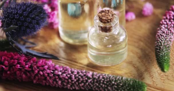 Парфуми, запах, аромат у скляних пляшках серед свіжих квітів, вид збоку . — стокове відео