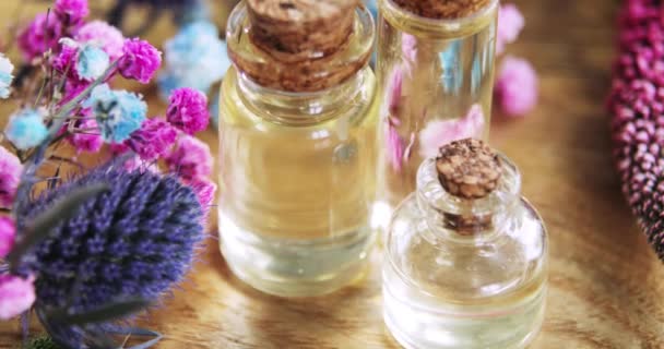 Huile essentielle, parfum en bouteilles de verre avec bouchons de liège parmi les fleurs fraîches . — Video