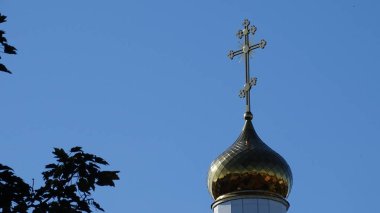 Mavi gökyüzüne karşı, Ortodoks haçı ile süslenmiş yaldızlı bir kubbe..