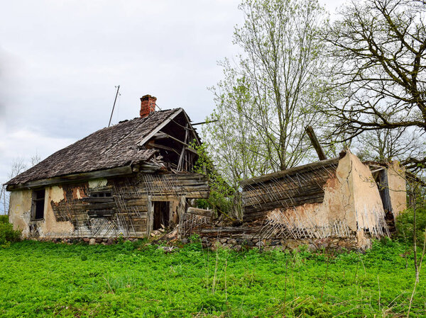 landscape with old and collapsed country house, collapsed wall and old wooden logs