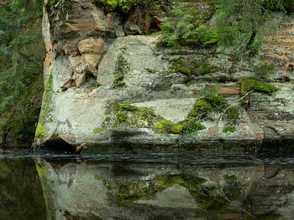 Krajobraz ze stromą rzeką i jaskiniami na piaskowcowym klifie — Zdjęcie stockowe