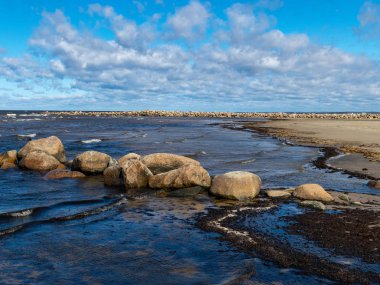  Kayalık deniz kıyıları, gökyüzünde beyaz bulutlar