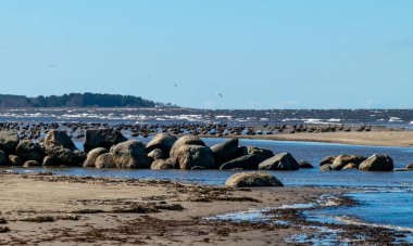 Kayalık deniz kıyıları, gökyüzünde beyaz bulutlar