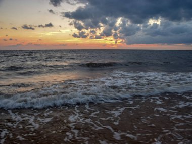 Sahilde güzel gün batımı manzarası, muhteşem gökyüzü ve denizin üzerindeki bulutlar.