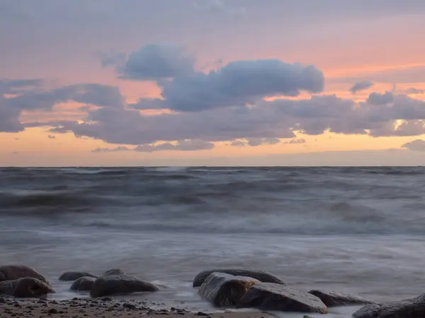 美丽的落日风景在岩石的海滩上 朦胧的波浪和岩石在前景 — 图库照片
