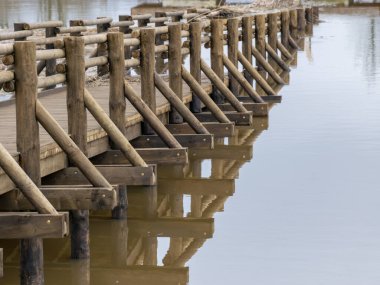 Baharda taşan nehir manzarası, nehir suyuna batırılmış tahta yaya köprüsü.