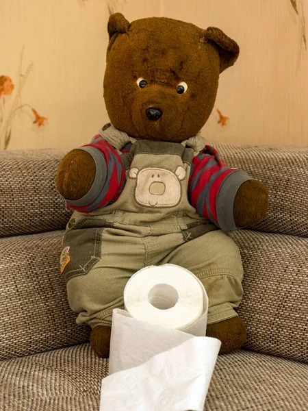a very old sad teddy bear with toilet paper