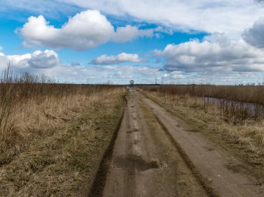 Toprak yollu bahar manzarası ve arka planda kuş izleme kulesi