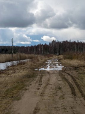 Baharın başlarında, ön planda pürüzlü bir dokusu olan toprak bir yol.