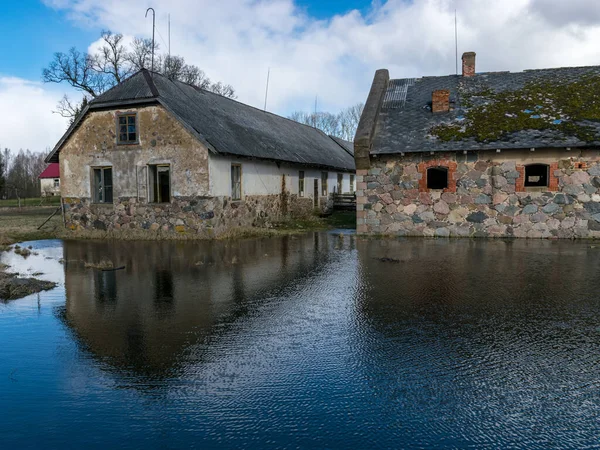Eski taş evlerin olduğu manzara, ön planda su yansımaları.