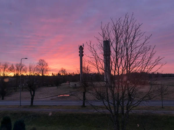 美しい日の出と明るい赤い空と木と水の塔のシルエットの風景 — ストック写真