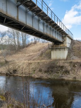 Küçük nehrin üzerindeki demiryolu köprüsü, mavi gökyüzüyle güneşli bahar günü