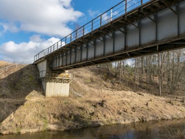 Küçük nehrin üzerindeki demiryolu köprüsü, mavi gökyüzüyle güneşli bahar günü