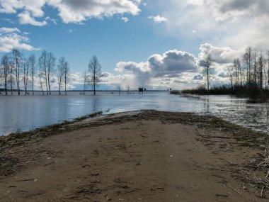 Baharda sular altında kalan bir göl manzarası, sahile giden yol suyla bitiyor.