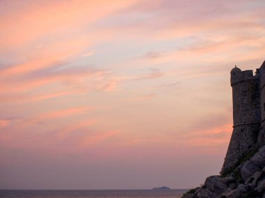 Pembe günbatımı gökyüzü, eski taş kule silueti