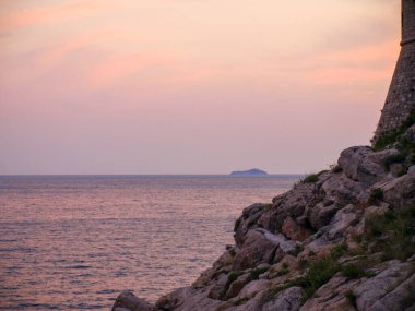 Pembe günbatımı gökyüzü, eski taş kule silueti