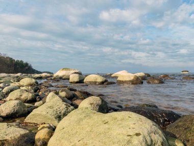 Güneşli bir günde birçok taşlı mavi deniz manzarası, Kaltene kıyısı, Letonya
