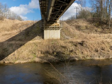 Küçük nehrin üzerindeki demiryolu köprüsü, mavi gökyüzüyle güneşli bahar günü