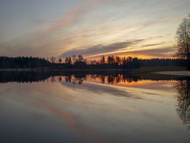 Pembe ve mor gün doğumu göldeki ayna görüntüleriyle, Vaidava Gölü, Letonya