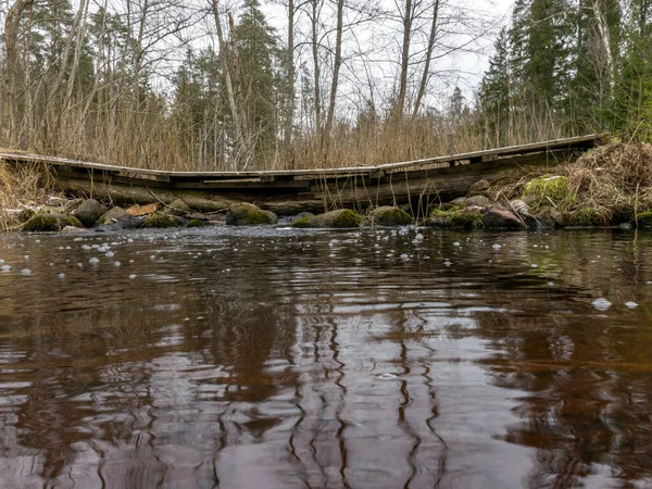 Küçük nehir üzerinde ahşap köprüsü olan manzara, sakin nehir suyundaki güzel yansımalar, bahar.