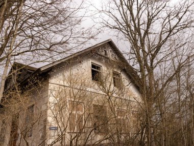 Kuja nehri üzerindeki Masonry köprüsü, açık mavi gökyüzü ile güneşli bir bahar günü, geçen yılın çimleriyle kaplanmış küçük bir nehrin kıyıları. Sudaki ağaç yansımaları, Kuja nehri, Letonya