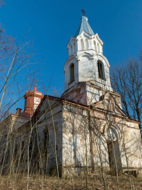 Mavi gökyüzüne karşı güzel beyaz bir kilisenin bulunduğu manzara, kilise çalılara dönüştü, Karzdaba Ortodoks Kilisesi 1875 'te Letonya' da inşa edildi.