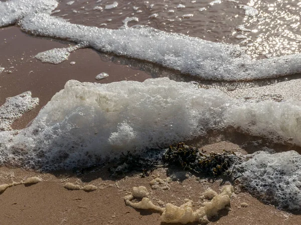 white foam on the sea shore, texture, abstract water reflections, sea sand, natural view of abstract photo concept