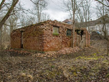 Eski kırmızı tuğlalı bir evin kalıntıları ve detaylarıyla yer kuru gri çimlerle kaplıdır.