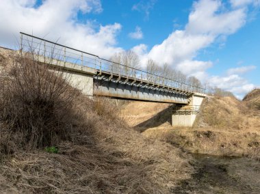 Küçük nehrin üzerindeki demiryolu köprüsü, mavi gökyüzüyle güneşli bahar günü