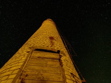 Gece gökyüzünde yıldızlarla aydınlatılmış tuğla bir kuleye sahip mistik bir gece manzarası