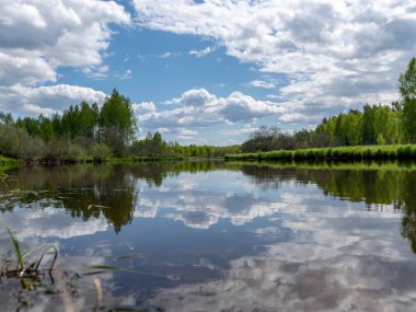 Baharda güzel bir nehri olan manzara, Sudaki bulut yansımaları, Seda Nehri, Letonya