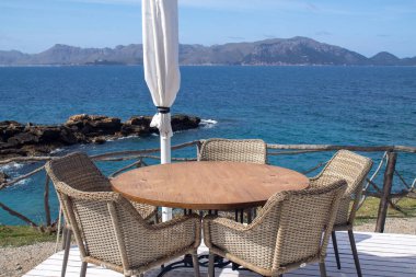 Kahvaltı ya da öğle yemeği için denize bakan teras. Gökyüzü ve bulutlarla mavi denizin güzel manzarası. Sakin bir gün için mükemmel..