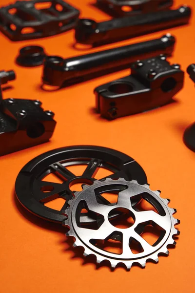 The gear of a BMX bike lies on an orange background. Different parts for extreme bike. Minimalism.